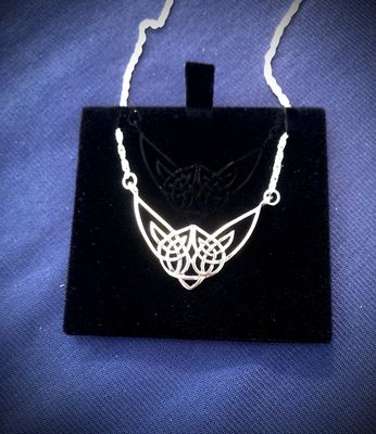 Sterling silver Highland Cow necklet, celebrating Scottish heritage and Celtic design, shown on black jewelry holder. 