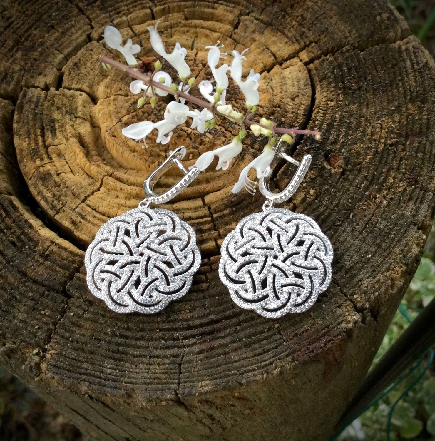 Sterling silver interlaced Celtic Knot earrings with sparkling cubic zirconia stones, statement Celtic jewelry; on bark. 