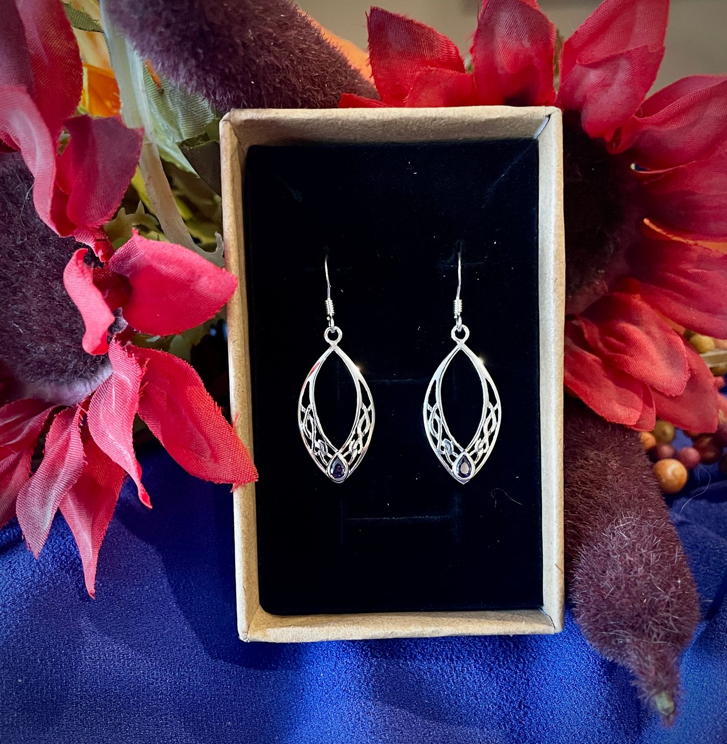 Sterling silver oval earrings featuring intricate Celtic knots and a radiant amethyst-colored stone, inspired by Scotland.