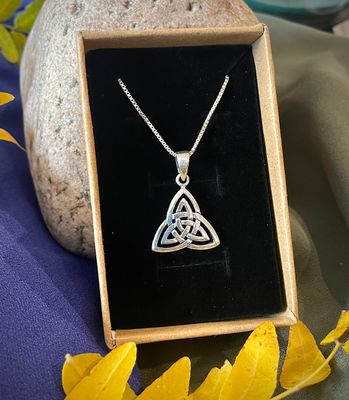 Sterling silver Celtic triquetra pendant necklace with intricate three-loop knot design, shown in jewelry box. 
