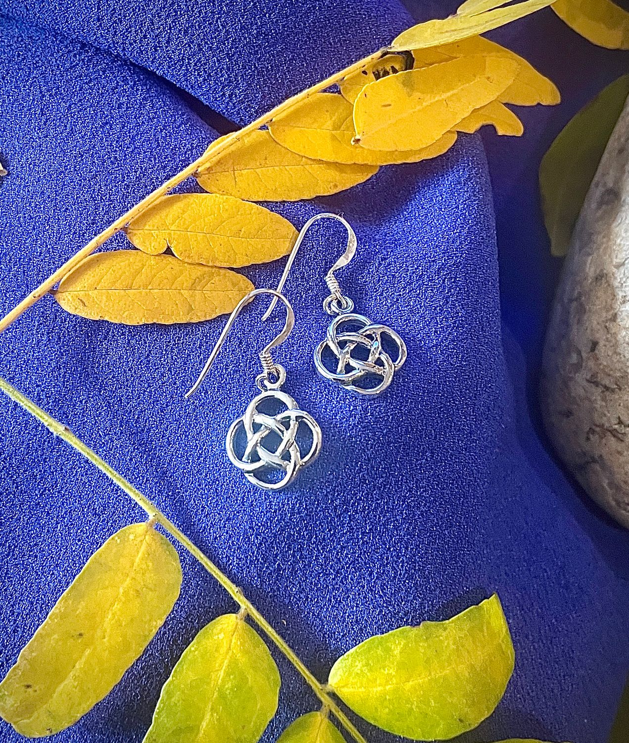 Elegant sterling silver earrings with classic Celtic knot pattern, representing love, loyalty, and eternity. On purple fabric