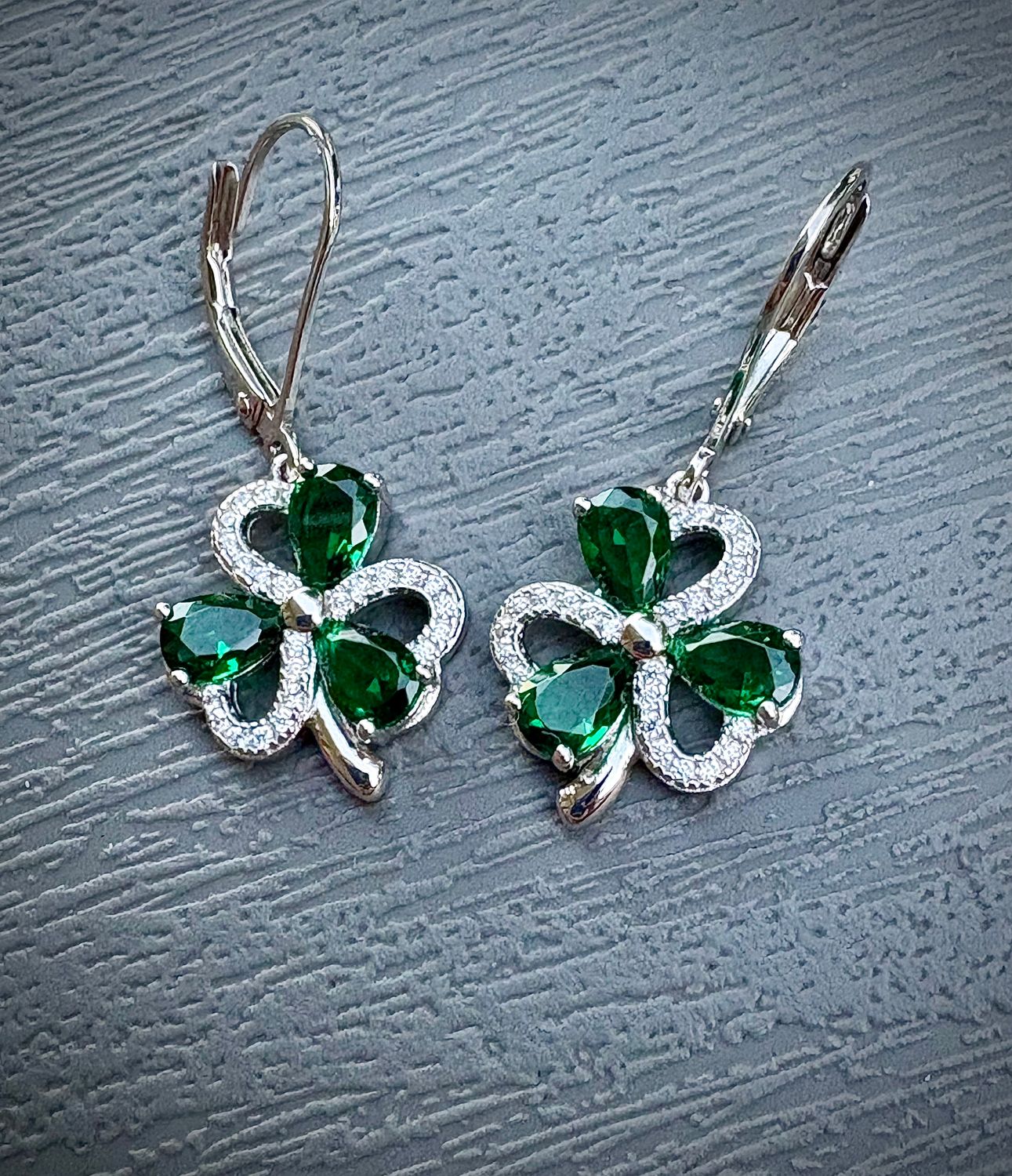 Sterling Silver and Cubic Zirconia Irish Shamrock Earrings with Lever Backs on Grey Background. 